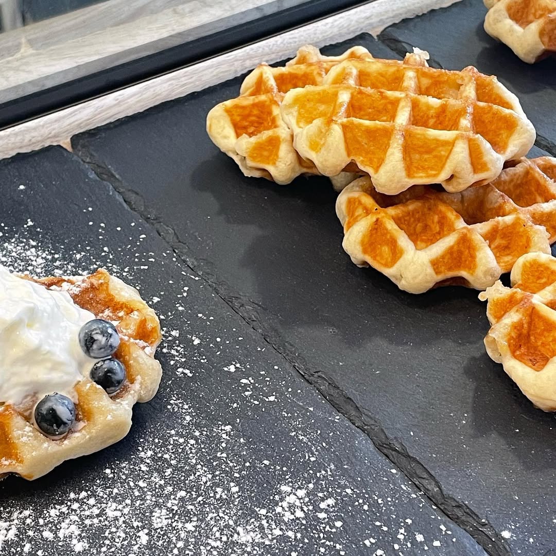 Waffles com mirtilos e açúcar em pó sobre tabuleiro escuro